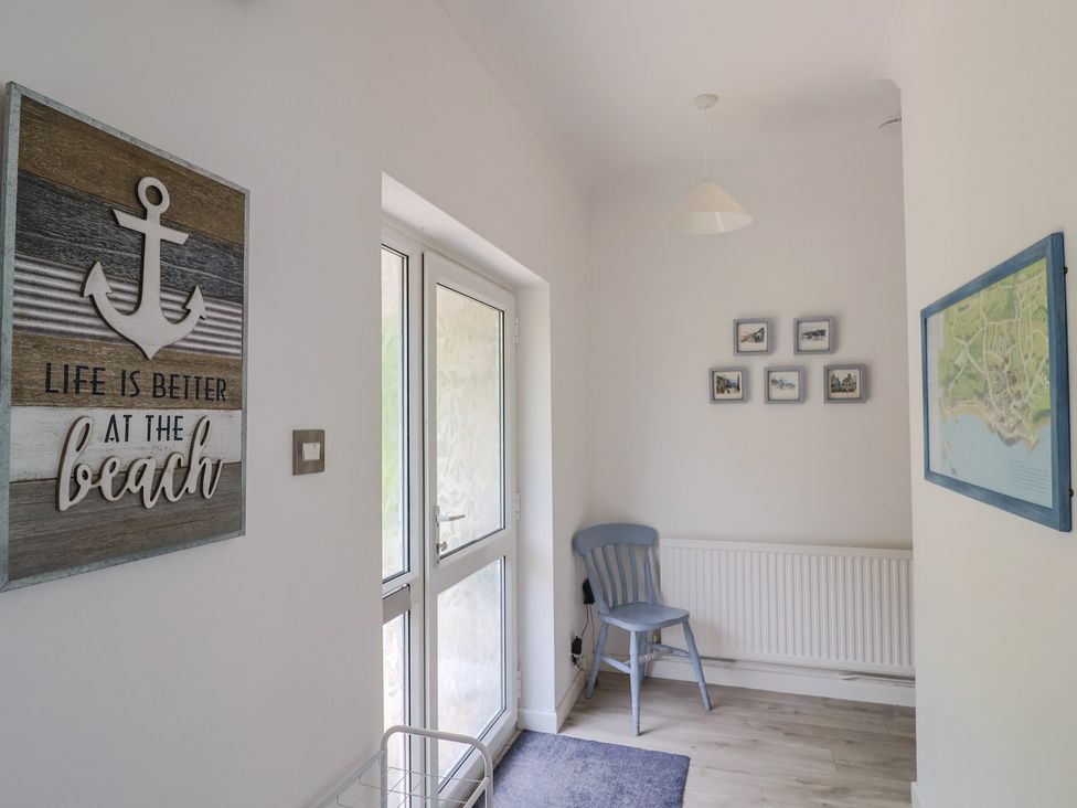 A hallway with wall art, a chair and a door at High Trees in Lyme Regis