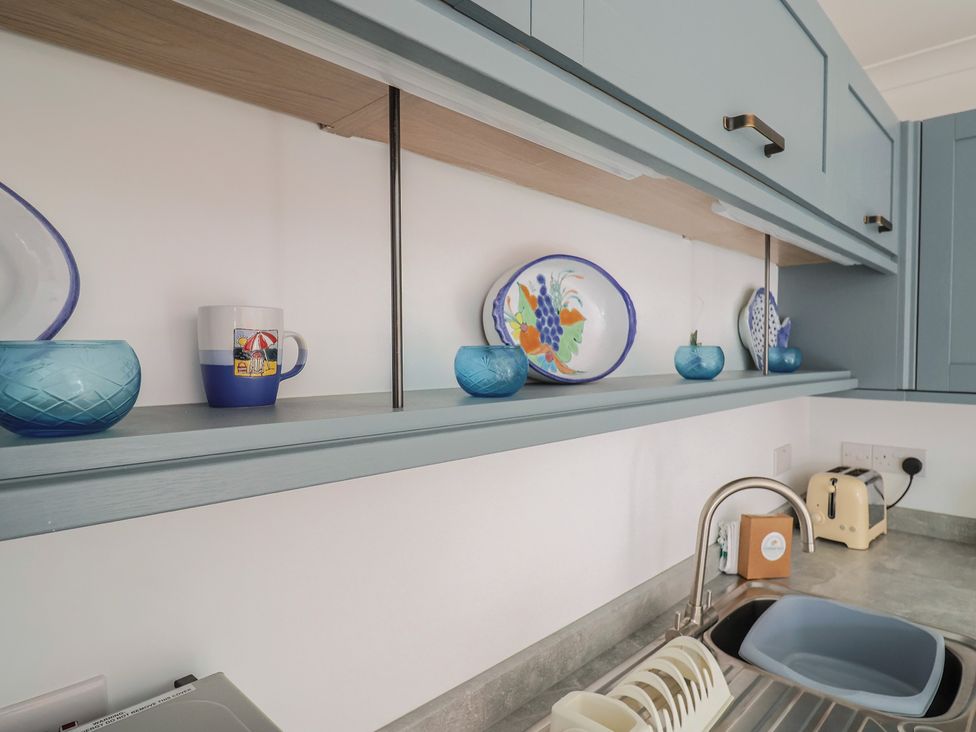 A kitchen with shelf containing dishes and a sink at 1 Bay View Court, Lyme Regis