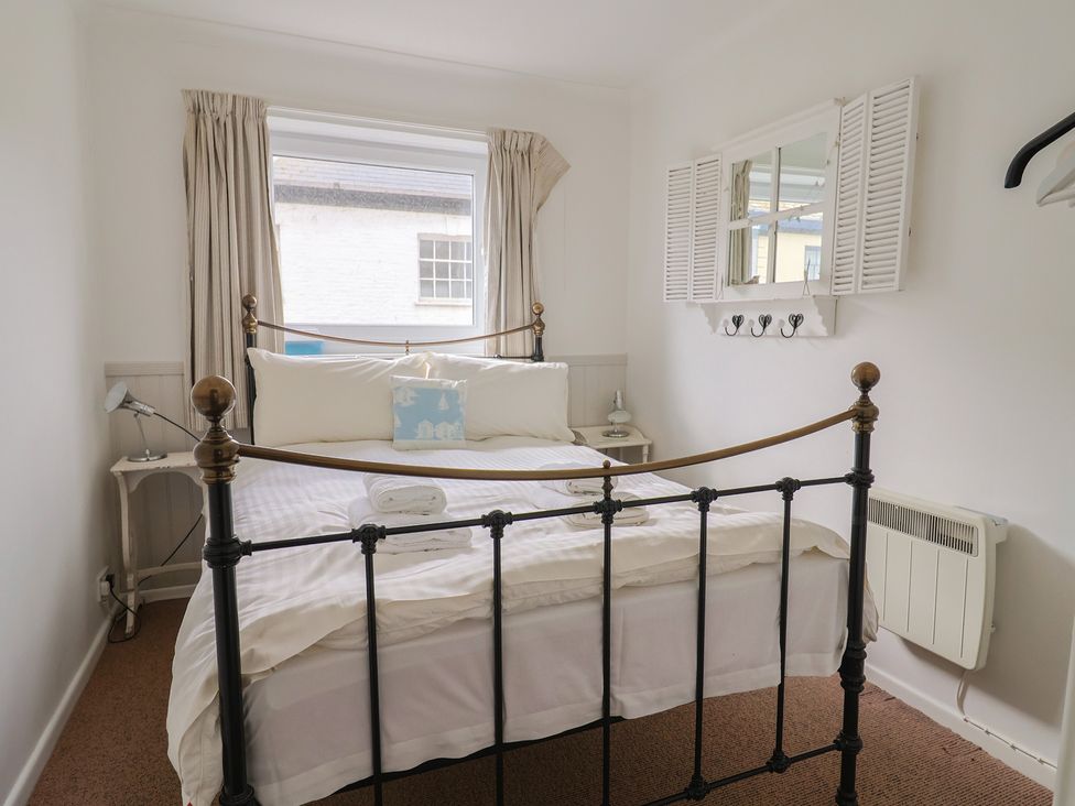 A bedroom with a bed, lamp and window at 1 Bay View Court in Lyme Regis