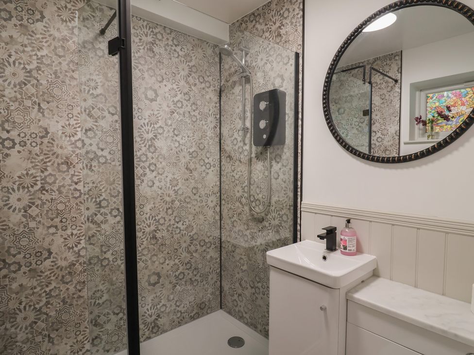 A bathroom featuring a shower, sink, and mirror at 1 Bay View Court Lyme Regis