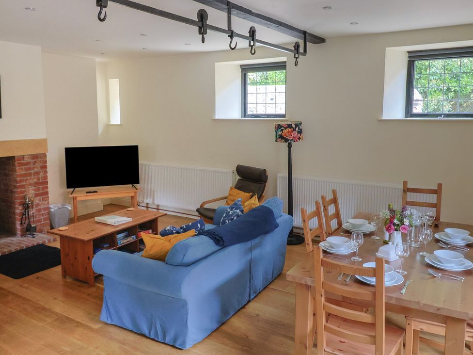 A living room with a sofa, television, and dining table at Yard Cottage in Rousdon