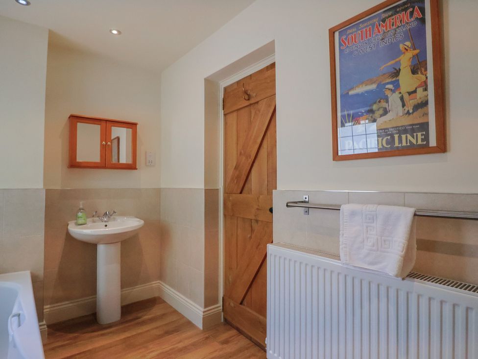 A bathroom with a sink and mirror at Yard Cottage in Rousdon