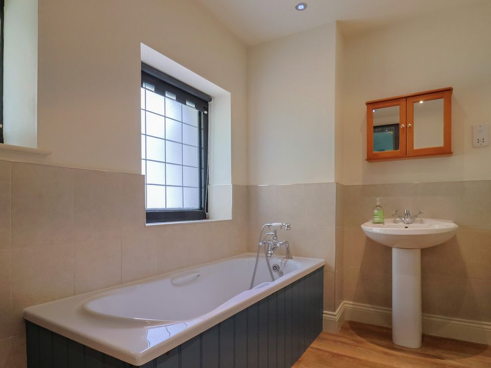 A bathroom with a bathtub and a washbasin at Yard Cottage, Rousdon