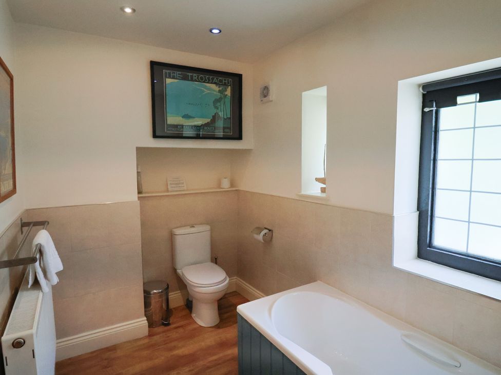 A bathroom with a bathtub and toilet at Yard Cottage Rousdon