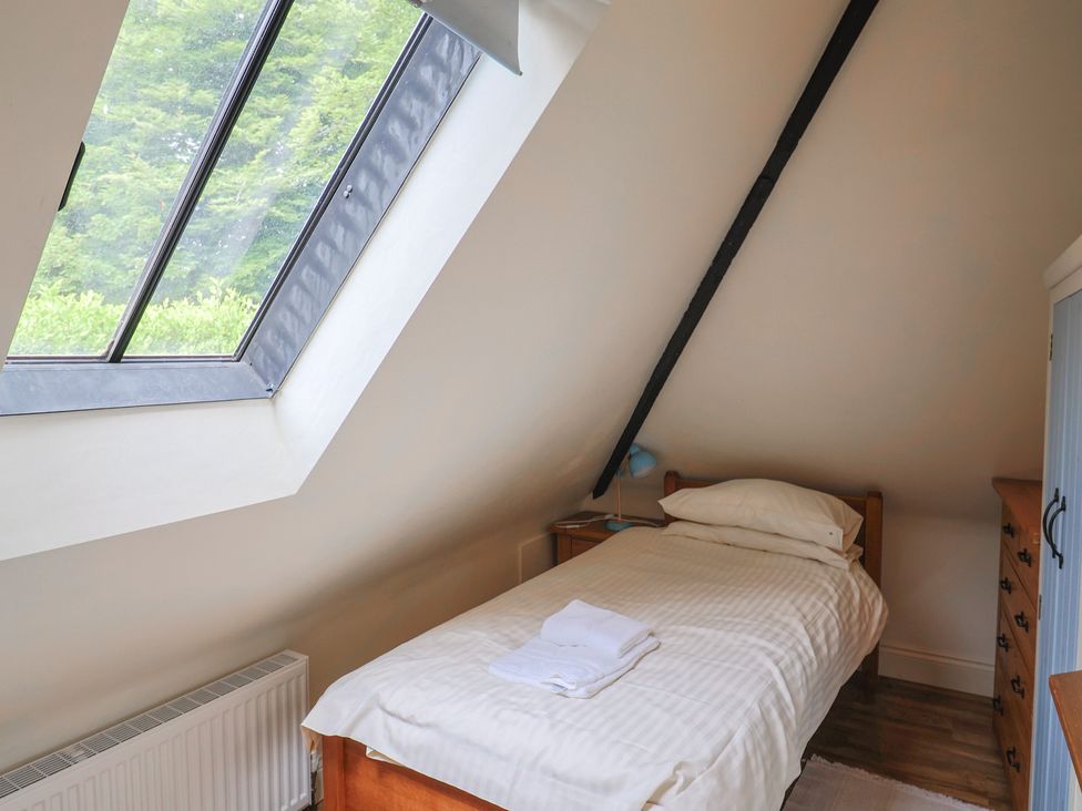A bedroom with a single bed and a window at Yard Cottage in Rousdon