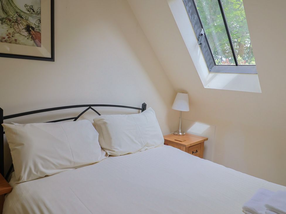 A bedroom with a bed and a lamp at Yard Cottage in Rousdon