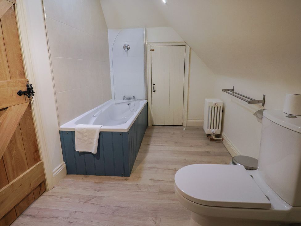 A bathroom with a bathtub and toilet at Yard Cottage in Rousdon