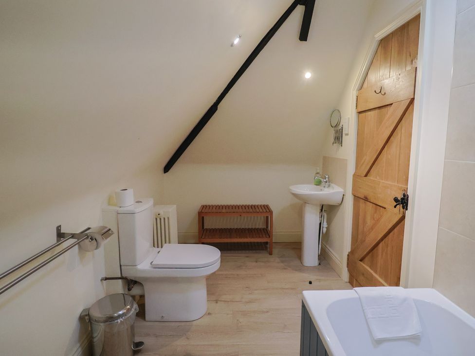 A bathroom containing a toilet, sink, and bath at Yard Cottage in Rousdon