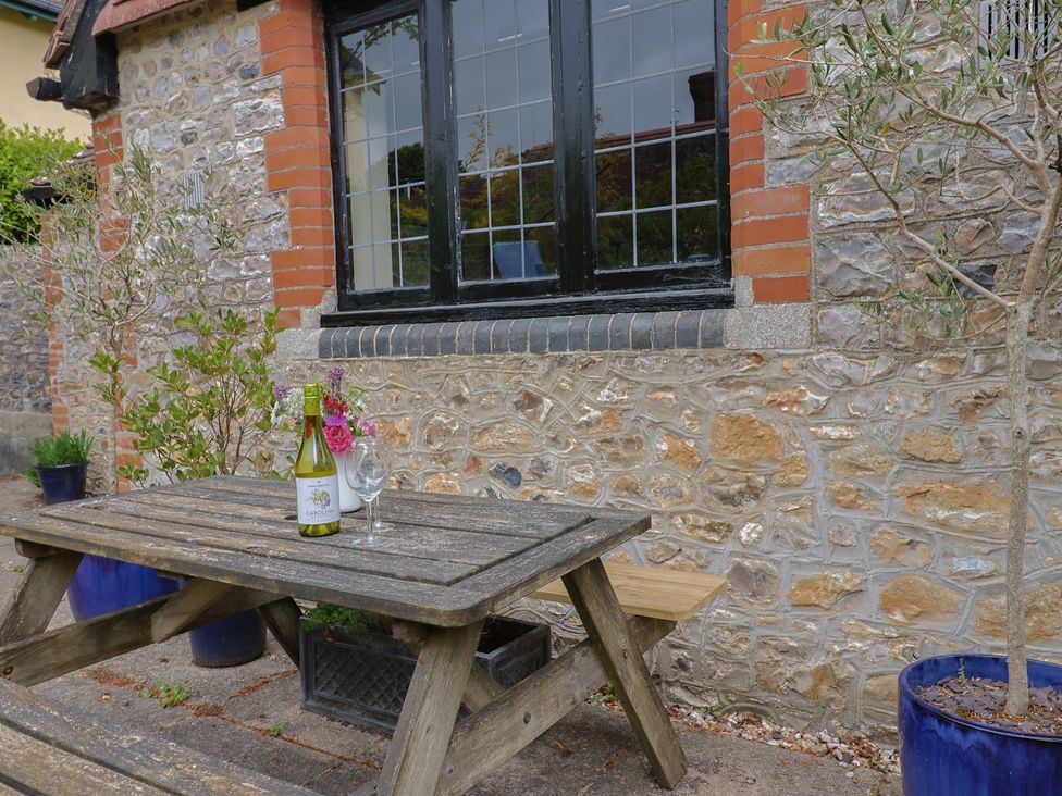 A table with a wine bottle and glasses outside at Yard Cottage in Rousdon