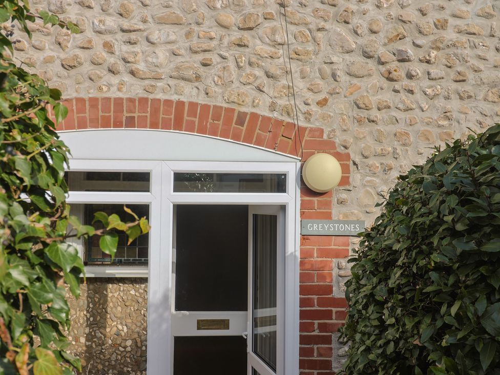 The entrance of Greystones with a sign and surrounding plants in Lyme Regis