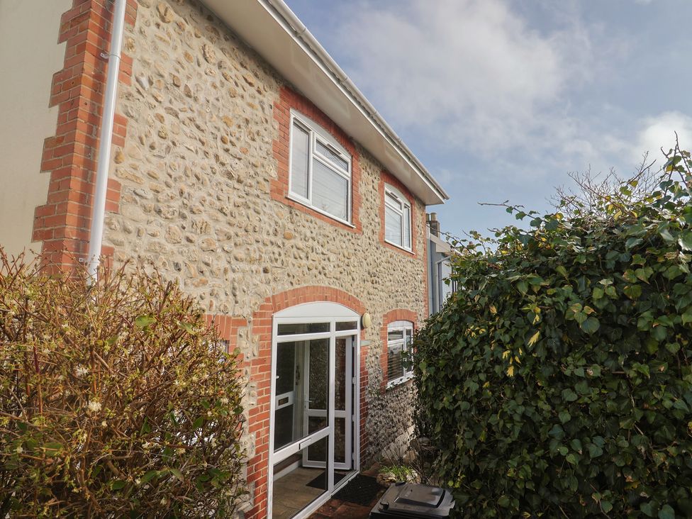 An exterior view of a house with a stone wall and shrubbery at Greystones Lyme Regis