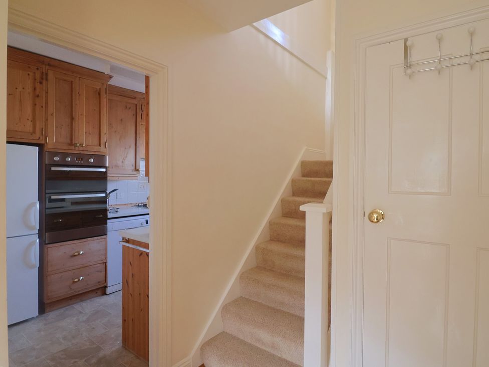 A kitchen with wooden cabinets and a staircase at Greystones Lyme Regis