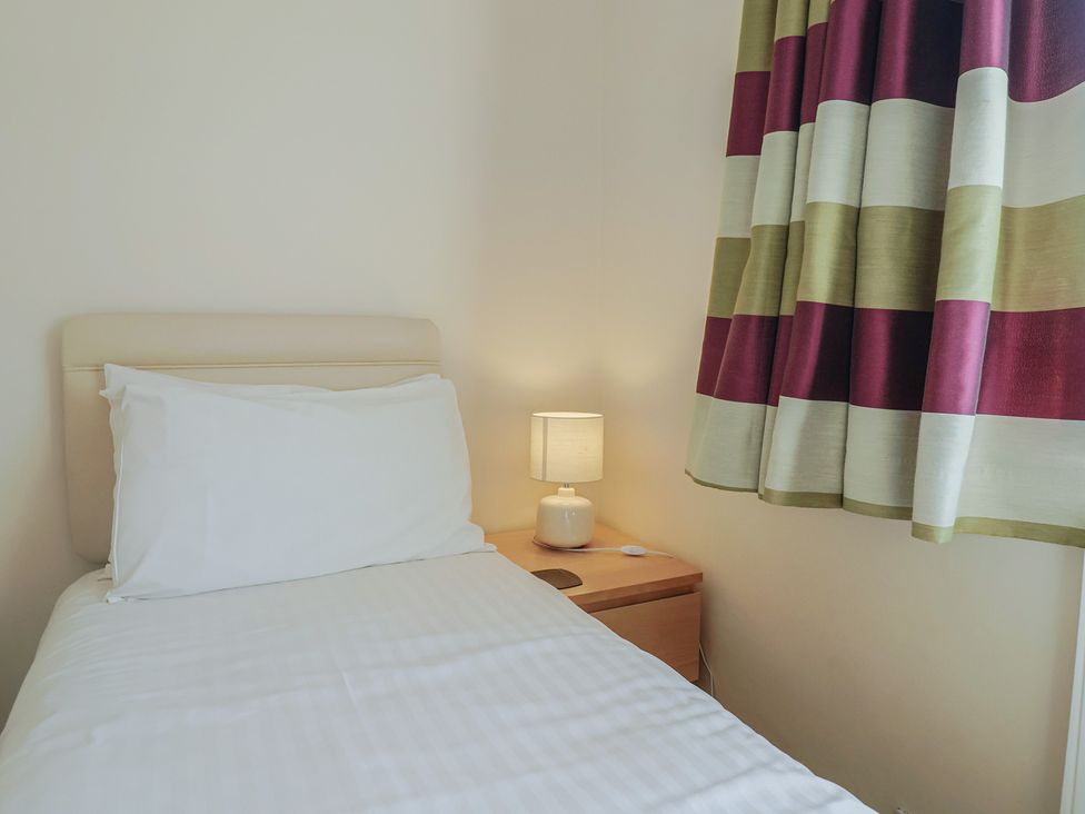 A bedroom with a bed and a lamp on the bedside table at Greystones Lyme Regis