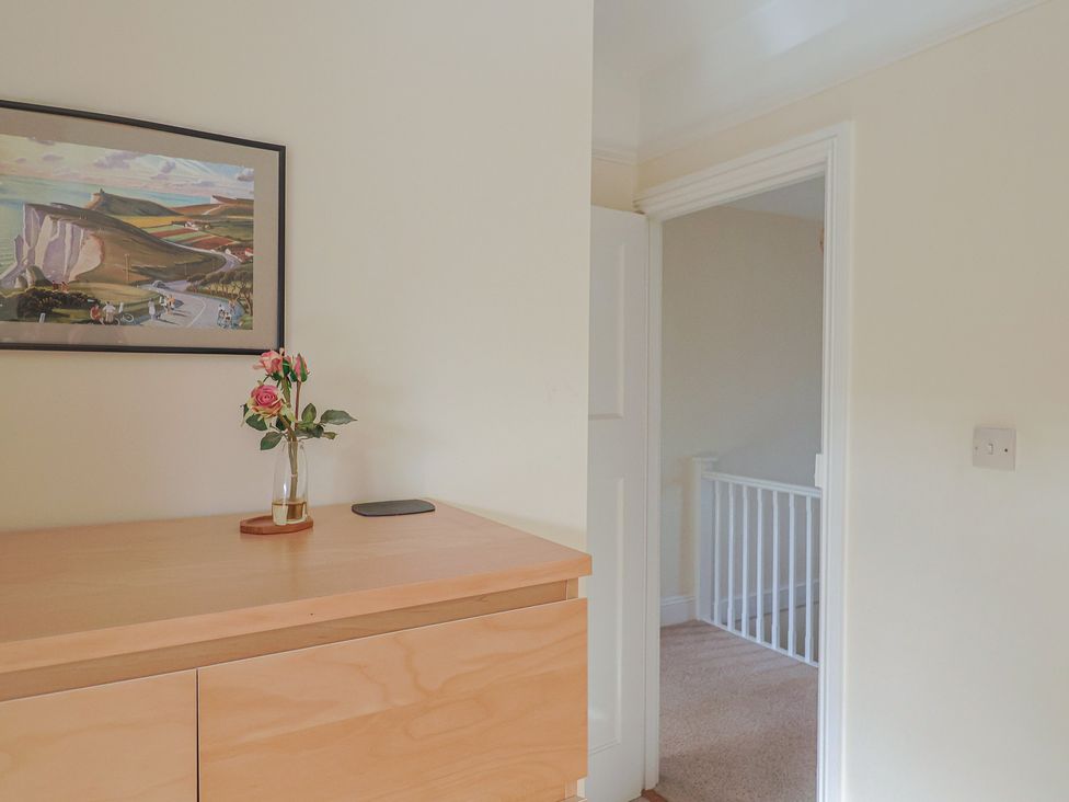 A hallway with a cupboard and a vase of flowers at Greystones Lyme Regis