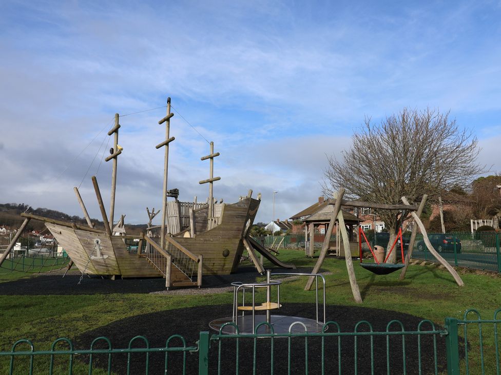A playground with a pirate ship structure and swings at Greystones Lyme Regis