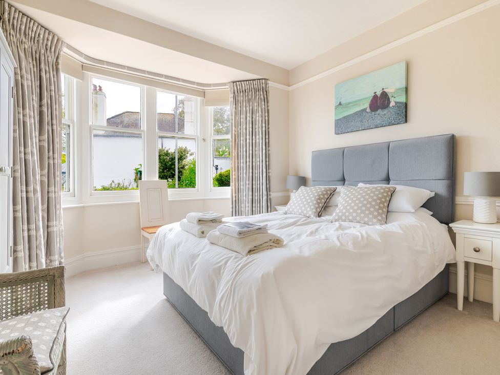 A bedroom with a bed and windows at 2 Hadleigh Villas in Lyme Regis