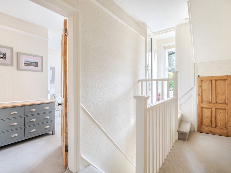 A hallway with a staircase and a dresser at 2 Hadleigh Villas Lyme Regis
