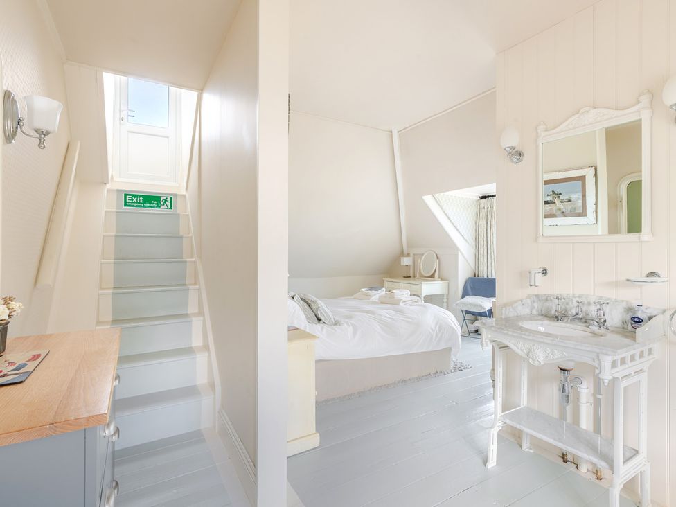 A bedroom with a bed, mirror, and stairs at 2 Hadleigh Villas in Lyme Regis