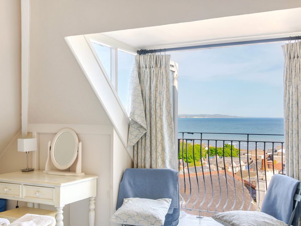 A bedroom with a desk and a sea view at 2 Hadleigh Villas in Lyme Regis