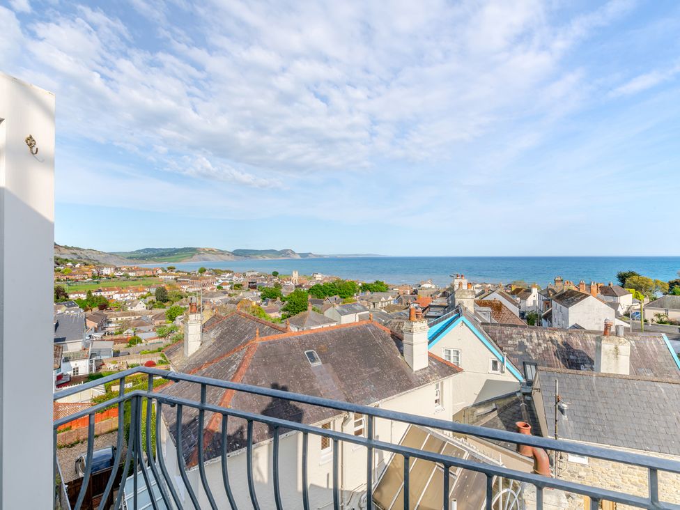 A view from a balcony overlooking roofs and the ocean at 2 Hadleigh Villas Lyme Regis