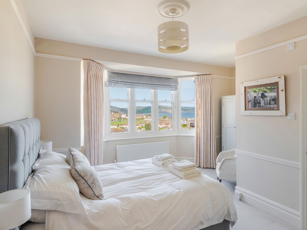 A bedroom with a bed, window, and lamp at 2 Hadleigh Villas in Lyme Regis