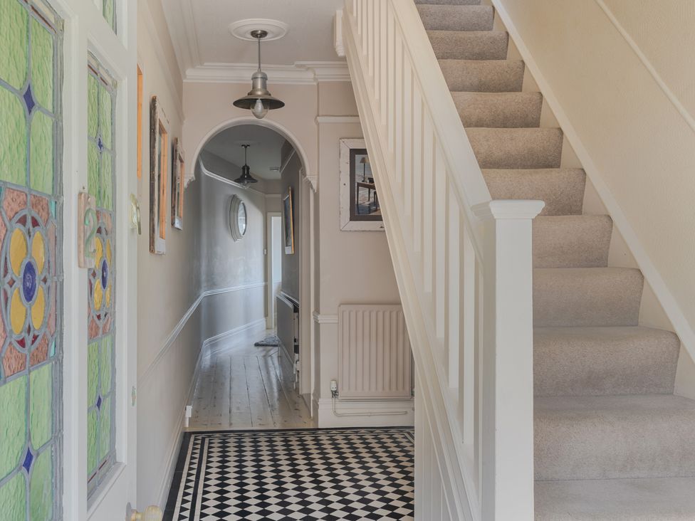 A hallway with a staircase and stained glass door at 2 Hadleigh Villas Lyme Regis