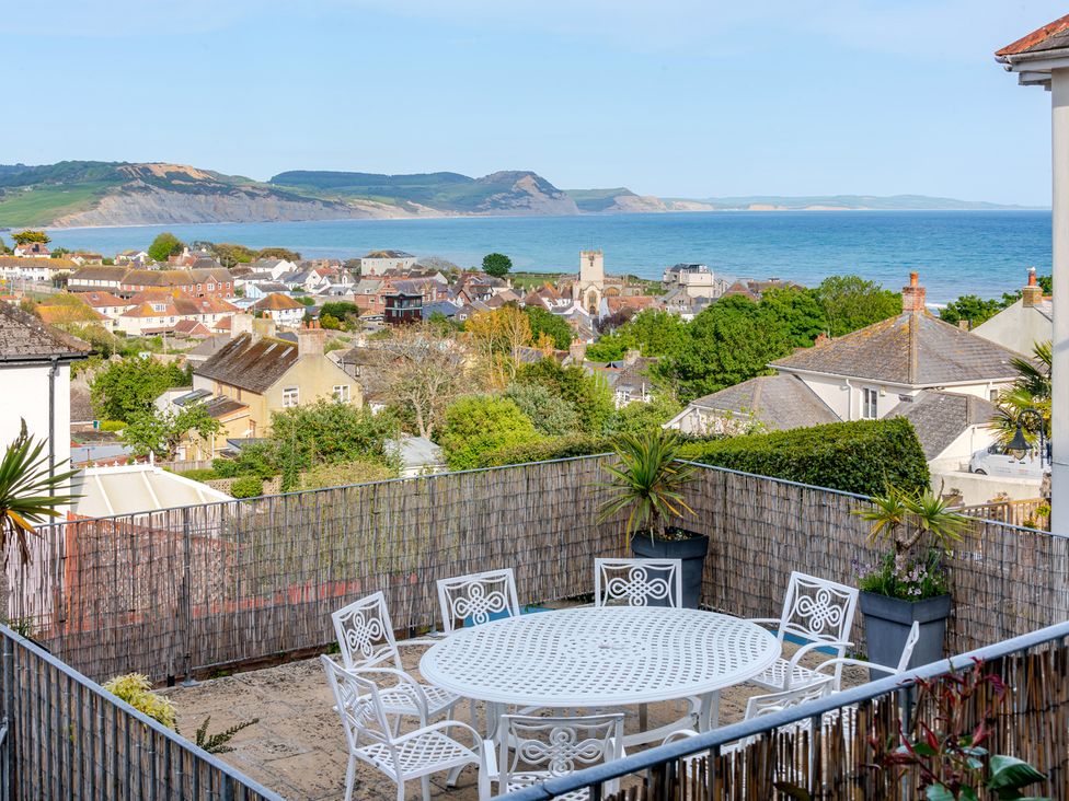 An outdoor space with a table and chairs overlooking the sea and hills at 2 Hadleigh Villas Lyme Regis