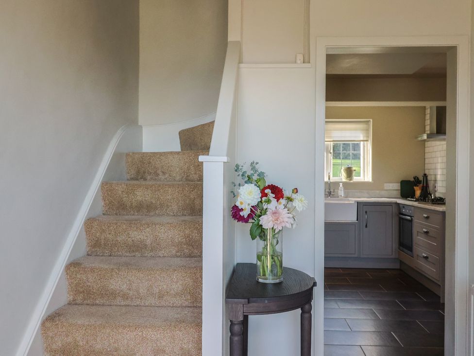 A hallway with a staircase leading to upper floors and a view into the kitchen at Westhaven in Lyme Regis