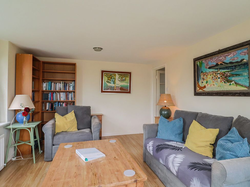 A living room with a sofa and bookshelf at Penny Plot Cottage in Lyme Regis