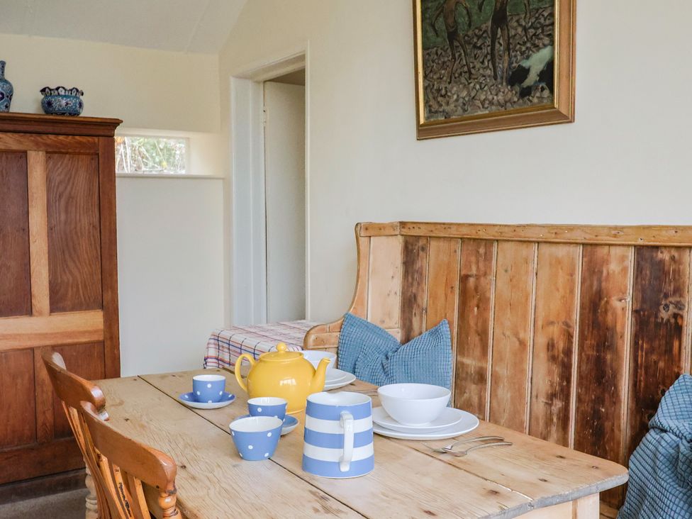 A dining room with a wooden table and chairs at Penny Plot Cottage in Lyme Regis