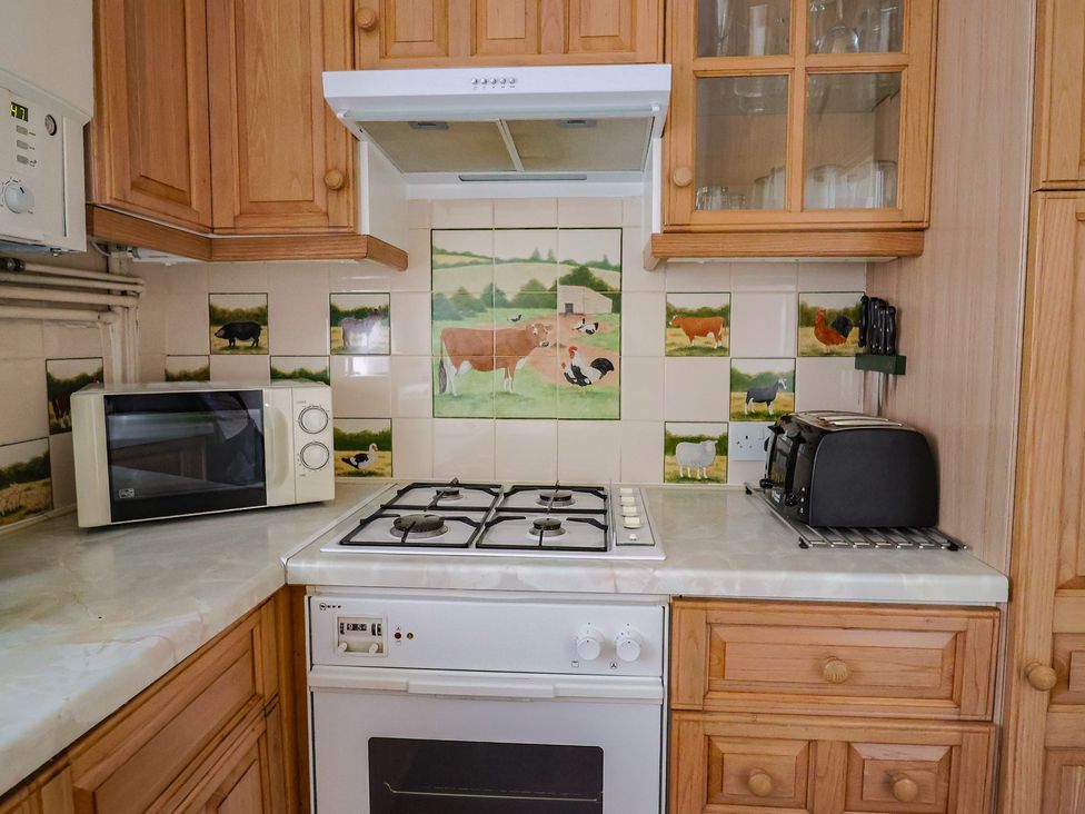 A kitchen with a gas stove and microwave at Penny Plot Cottage in Lyme Regis
