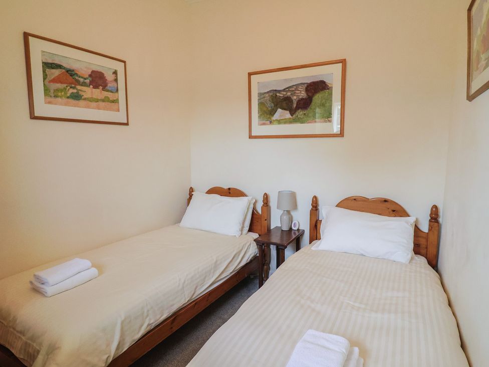 A bedroom with two single beds and framed artwork at Penny Plot Cottage in Lyme Regis