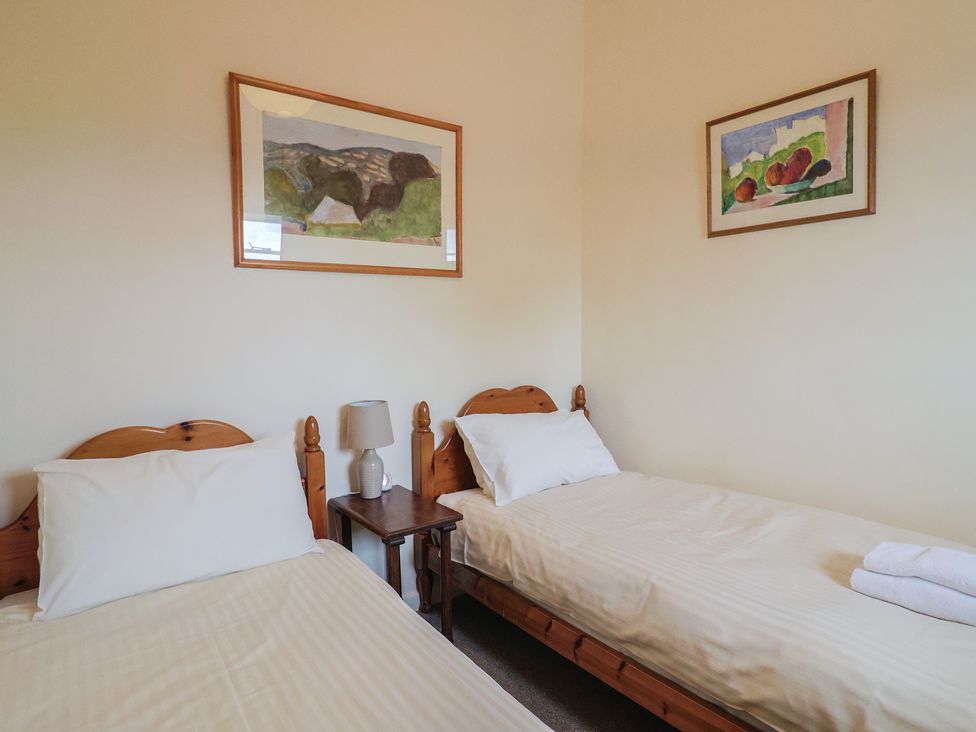A bedroom with two single beds and artwork on the walls at Penny Plot Cottage Lyme Regis
