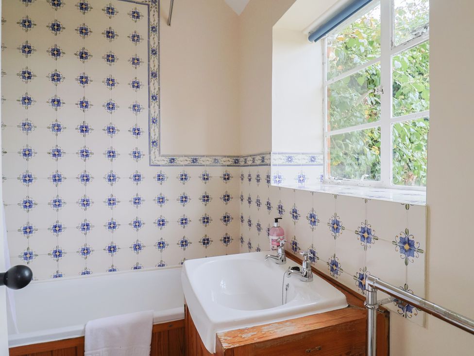 A bathroom with a bath tub and window at Penny Plot Cottage Lyme Regis