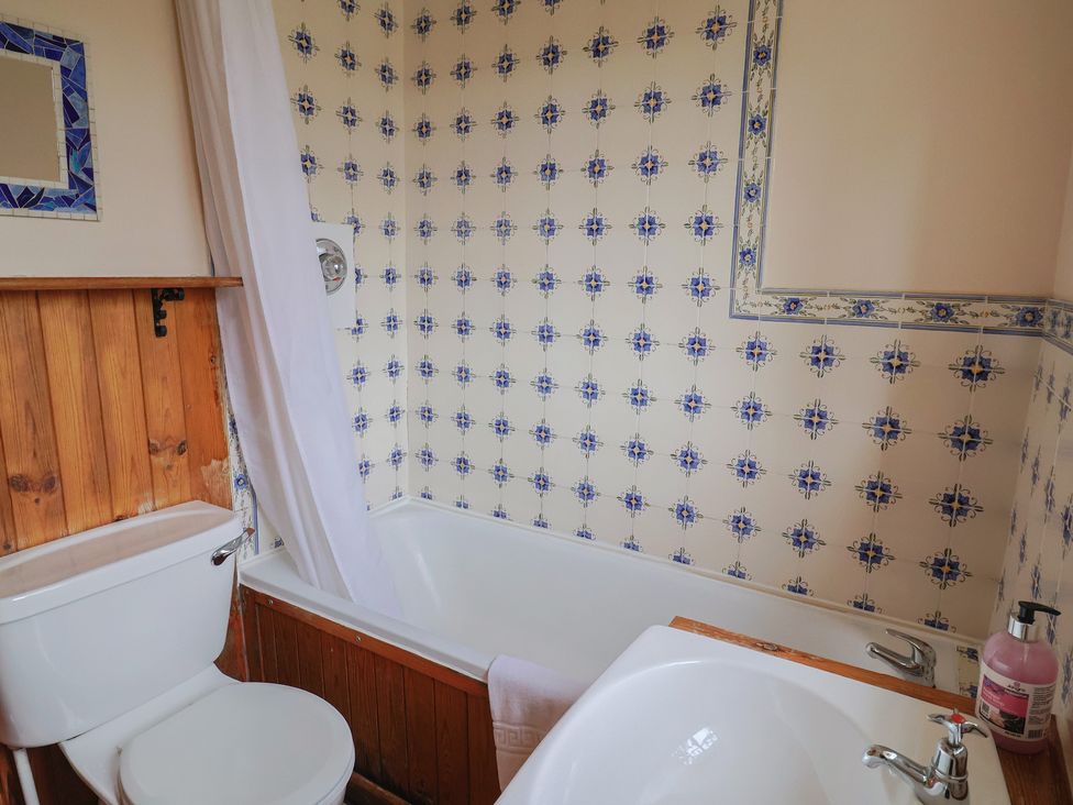A bathroom with a bathtub and a toilet at Penny Plot Cottage in Lyme Regis