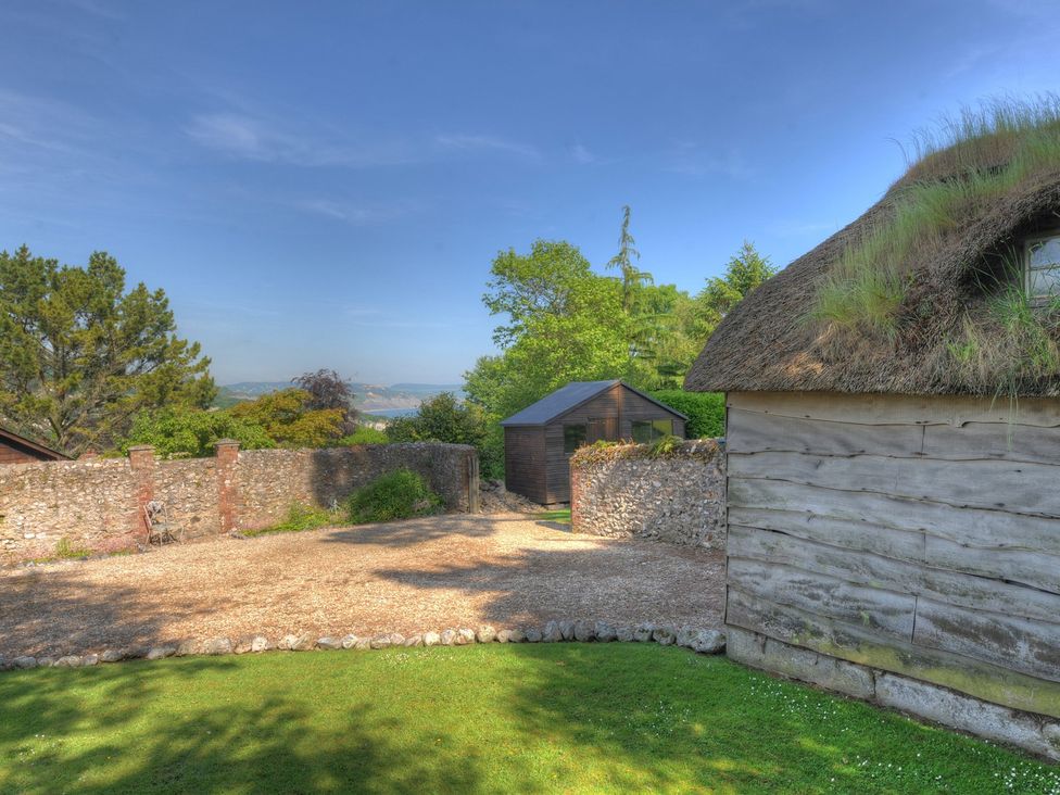 An outdoor area with a thatched building and shed at Penny Plot Cottage Lyme Regis