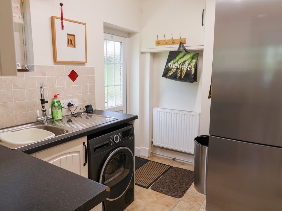 A kitchen with sink, washing machine, and fridge at Barn Close Farm in Morcombelake