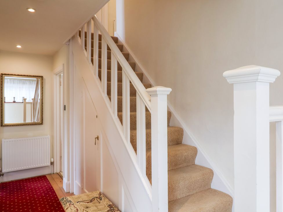 A hallway with a staircase and mirror at Barn Close Farm Morcombelake