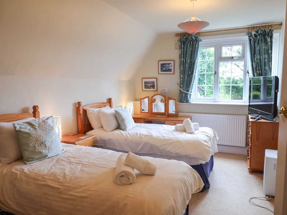 A bedroom with twin beds and a television at Barn Close Farm in Morcombelake
