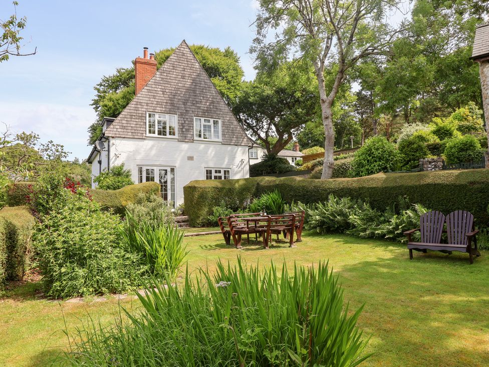 A garden with a house, table, and chairs at Barn Close Farm in Morcombelake