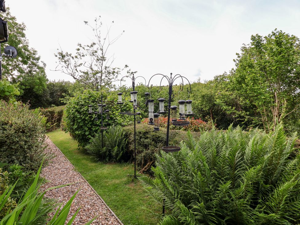 A garden with bird feeders and a pathway at Barn Close Farm Morcombelake
