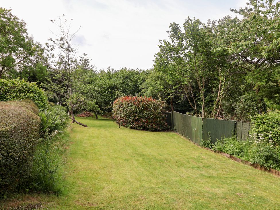 A garden with grass, trees, hedges, and a fence at Barn Close Farm Morcombelake