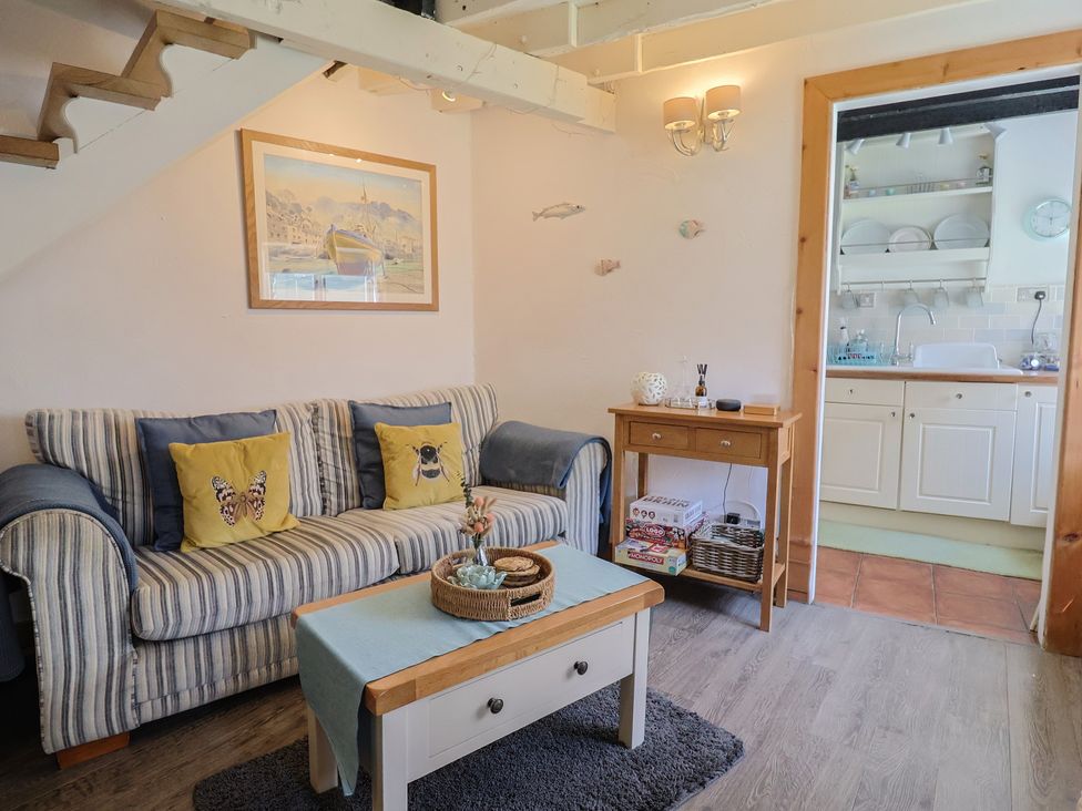 A living room with a sofa and kitchenette at Cleve Cottage in Lyme Regis