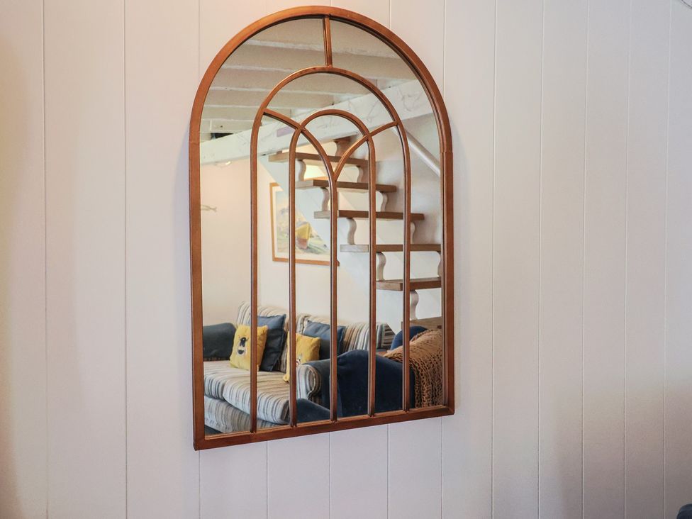 A mirror reflecting a staircase and a couch at Cleve Cottage in Lyme Regis