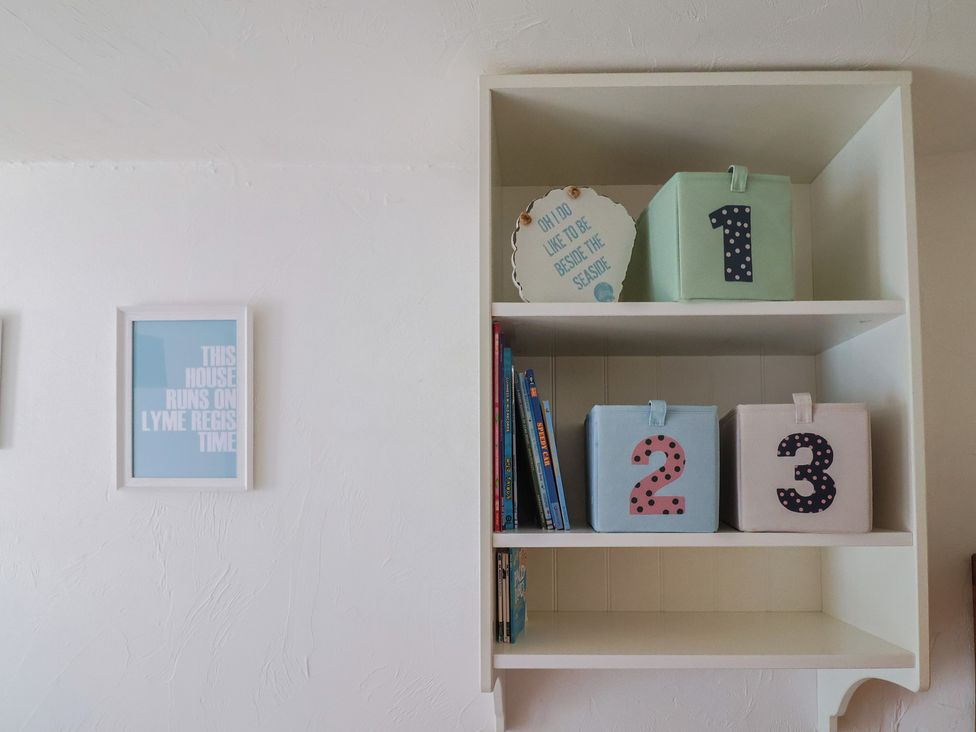 A shelf with storage boxes and books at Cleve Cottage in Lyme Regis