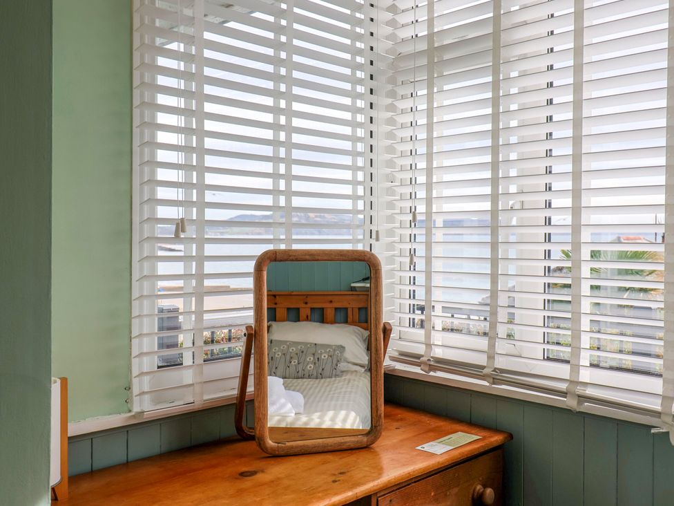 A bedroom with a mirror and window with blinds at 1 Wellhayes in Lyme Regis