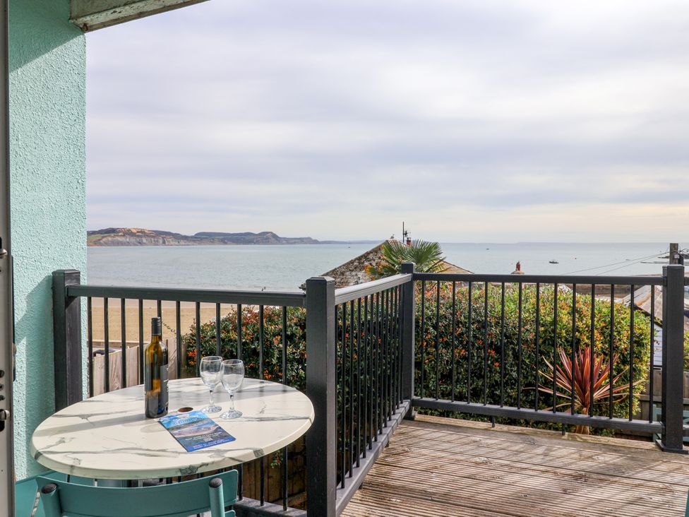 A balcony with a table and drinks overlooking the sea at 1 Wellhayes Lyme Regis