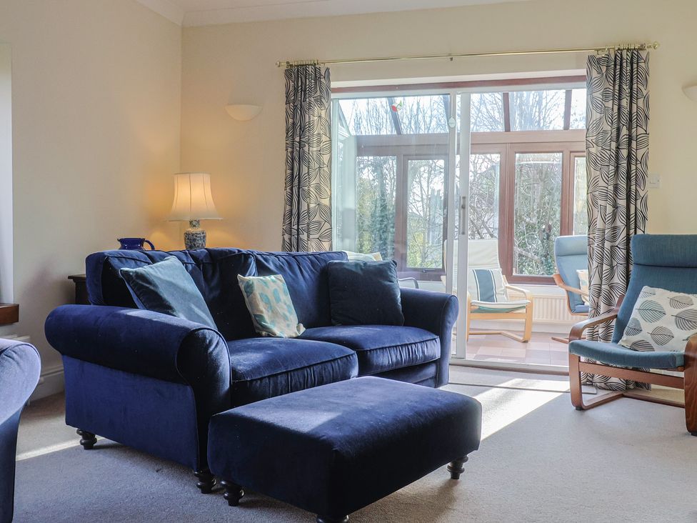 A living room with a blue sofa and glass door at High Cliff Orchard in Lyme Regis