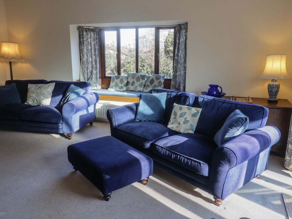 A living room with a blue sofa and ottoman at High Cliff Orchard in Lyme Regis