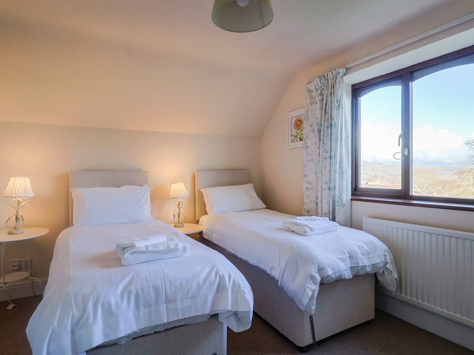 A bedroom with two single beds and a window at High Cliff Orchard in Lyme Regis